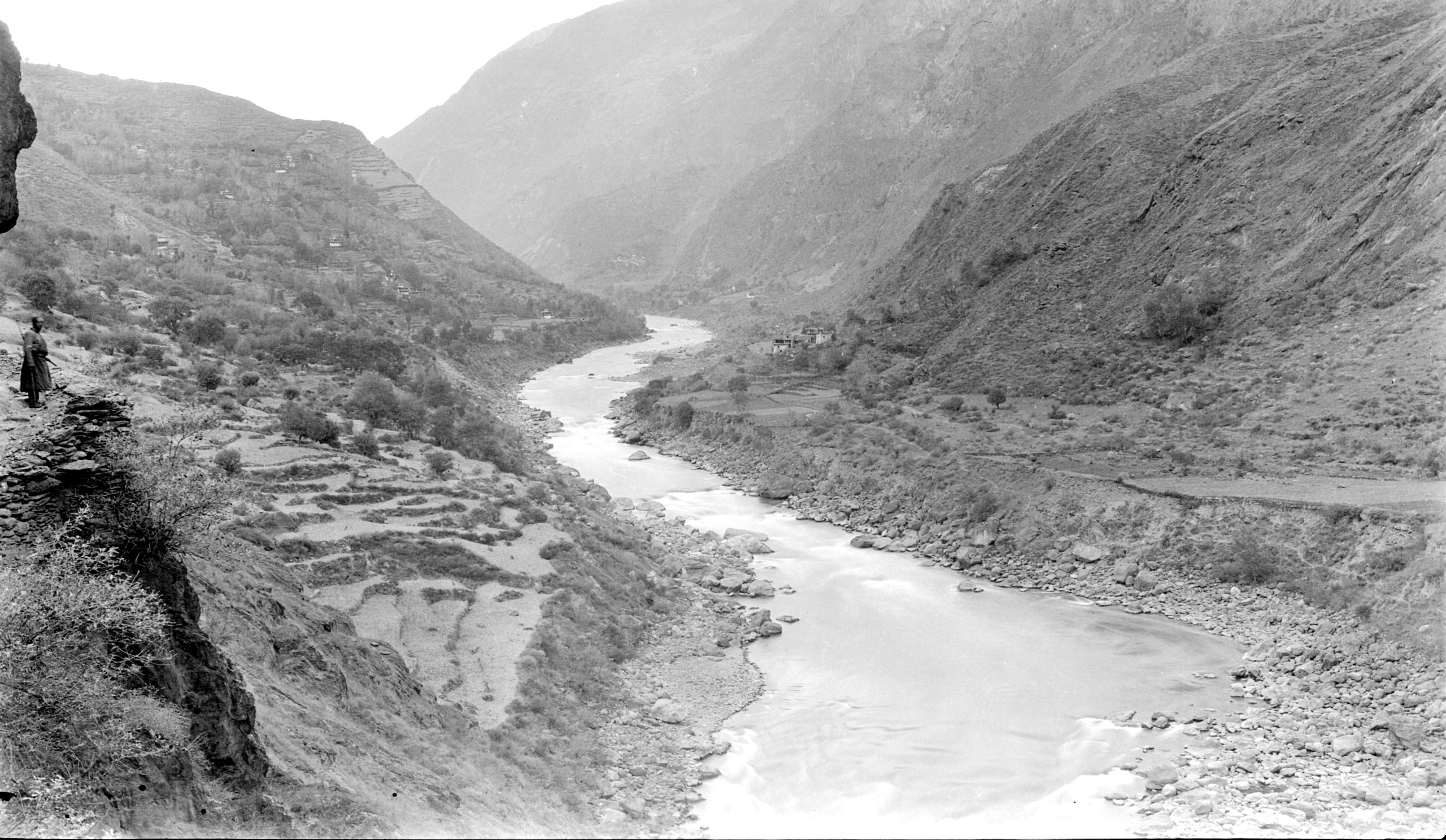Picture of a woman on a shelf looking over the river and terraces with the village of Ba-Wong (mid-distance)